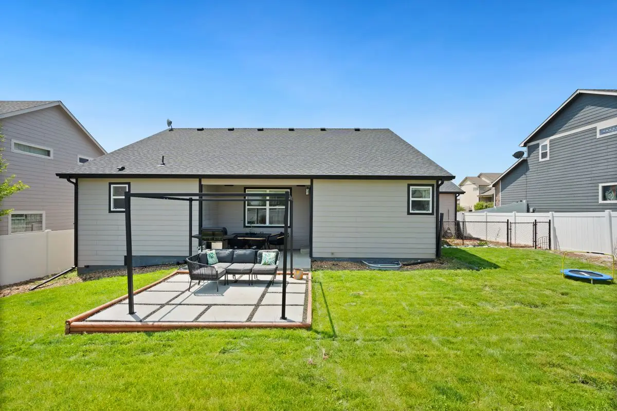 Concrete patio with seating in a fenced suburban backyard
